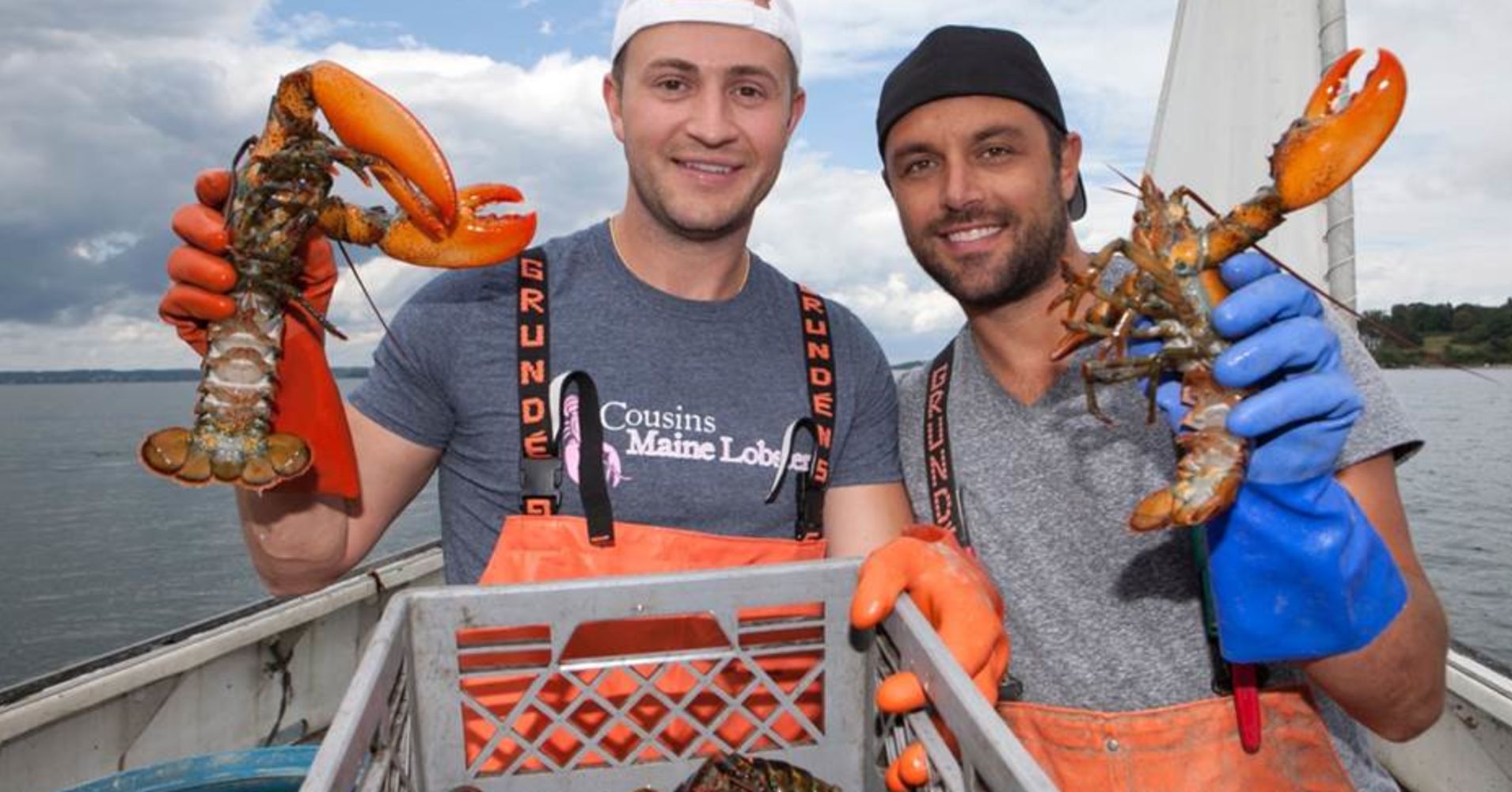 Two people holding lobsters in hands on a boat